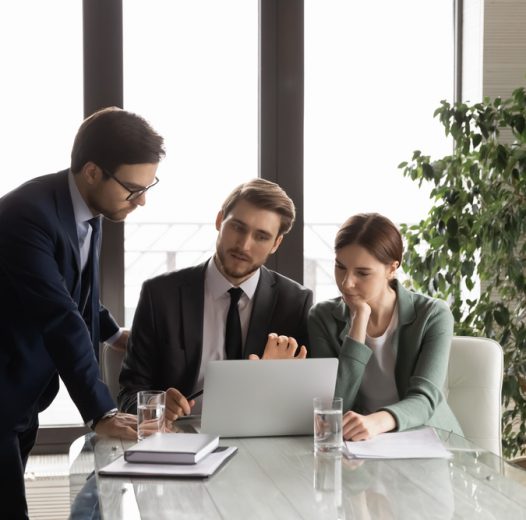 Concentrated,Diverse,Employees,Gather,In,Boardroom,Look,At,Laptop,Screen